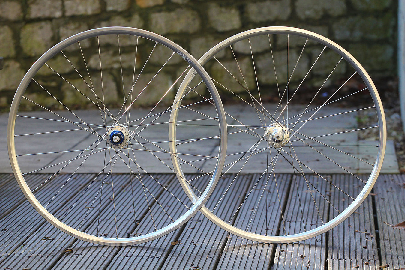 Close-up of bicycle wheels which are displayed on a wooden surface